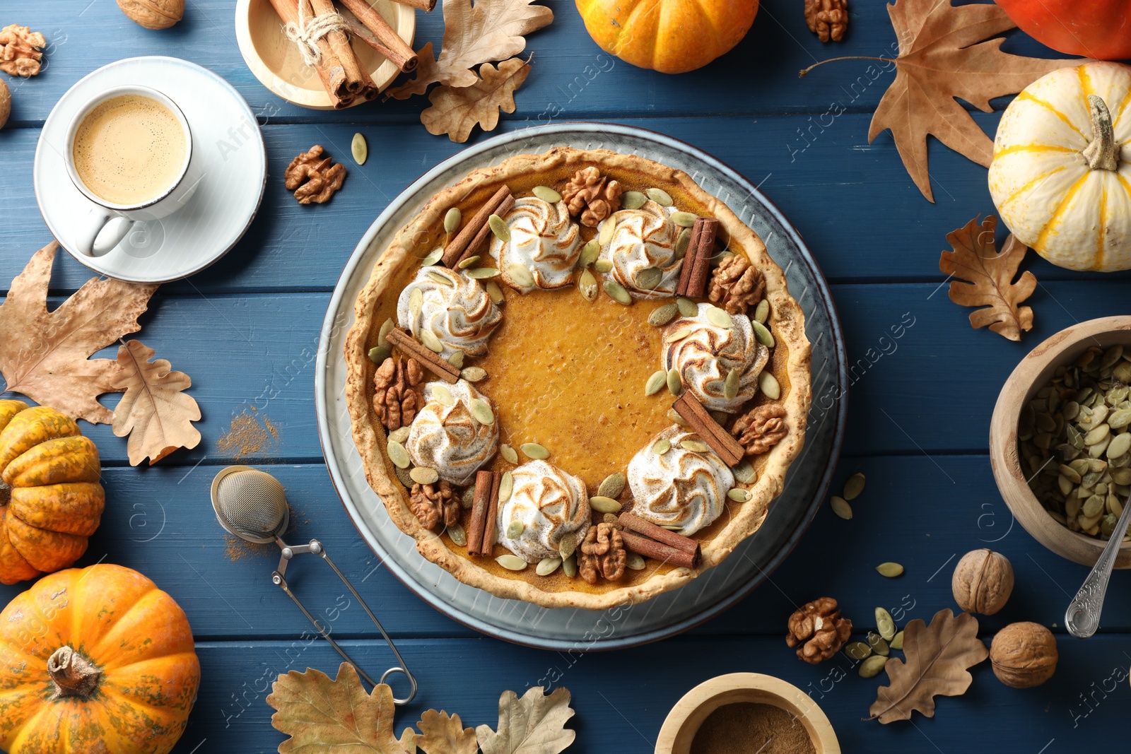 Photo of Flat lay composition with homemade pumpkin pie with whipped cream, seeds and cinnamon on blue wooden table