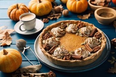 Photo of Homemade pumpkin pie with whipped cream, seeds and cinnamon on blue wooden table