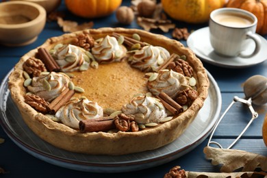 Homemade pumpkin pie with whipped cream, seeds and cinnamon on blue wooden table, closeup