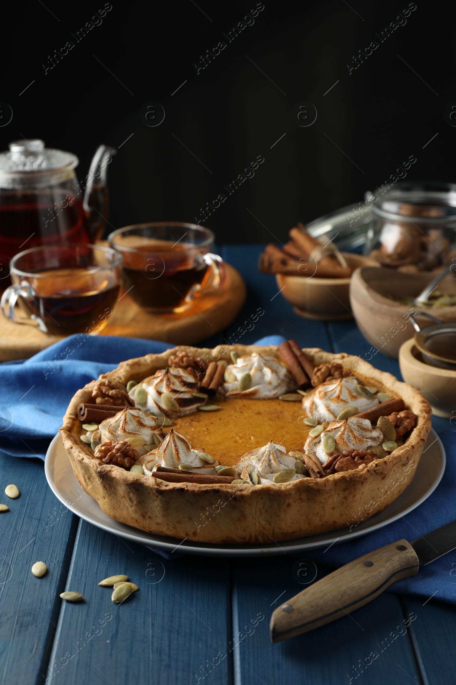 Photo of Homemade pumpkin pie with whipped cream, seeds and cinnamon on blue wooden table