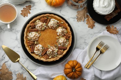 Flat lay composition with homemade pumpkin pie with whipped cream, seeds and cinnamon on white marble table