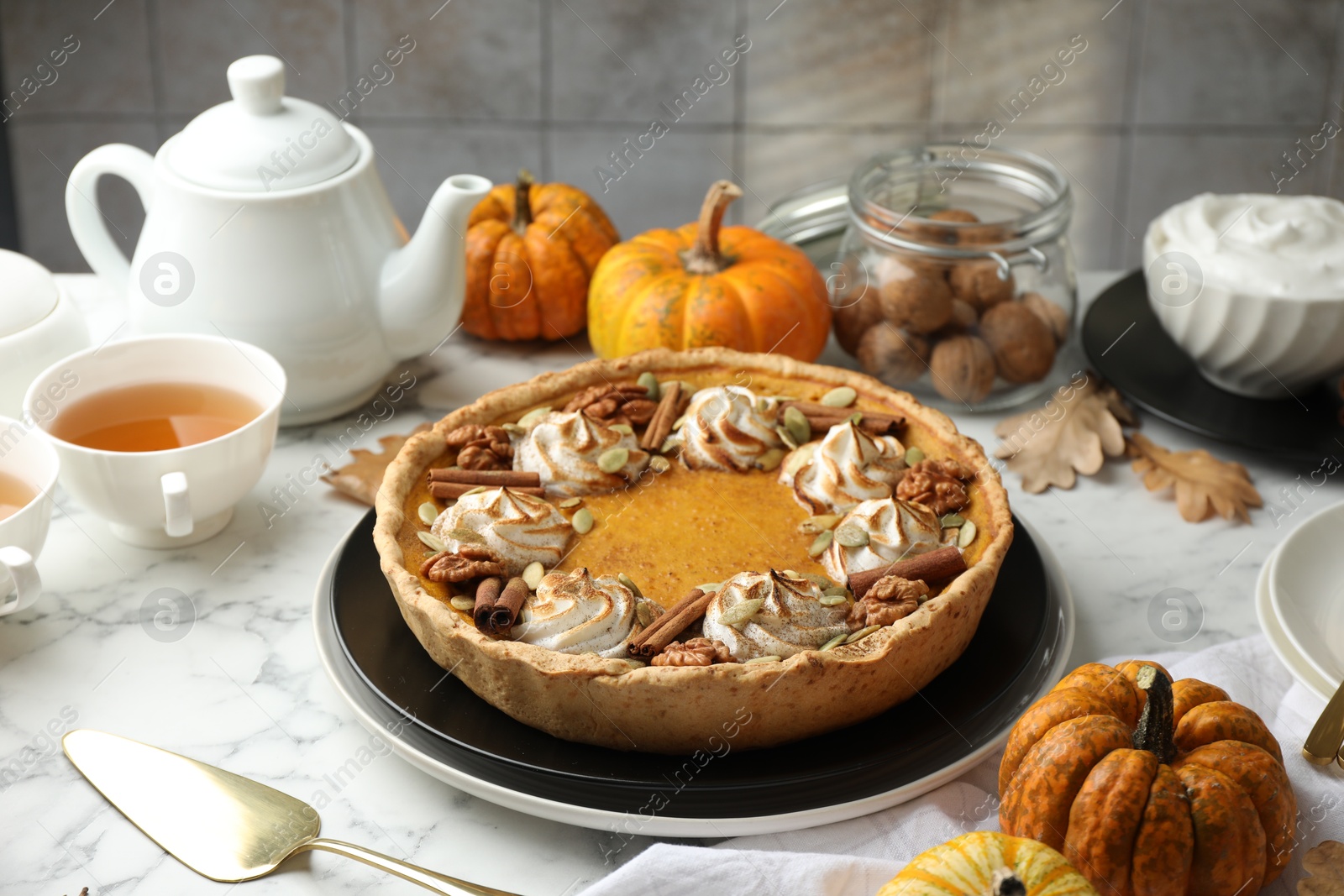 Photo of Homemade pumpkin pie with whipped cream, seeds and cinnamon on white marble table