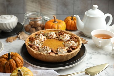 Photo of Homemade pumpkin pie with whipped cream, seeds and cinnamon on white marble table