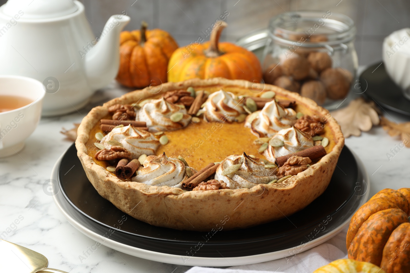 Photo of Homemade pumpkin pie with whipped cream, seeds and cinnamon on white marble table