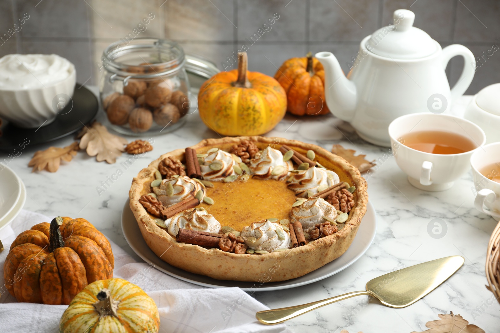 Photo of Homemade pumpkin pie with whipped cream, seeds and cinnamon on white marble table