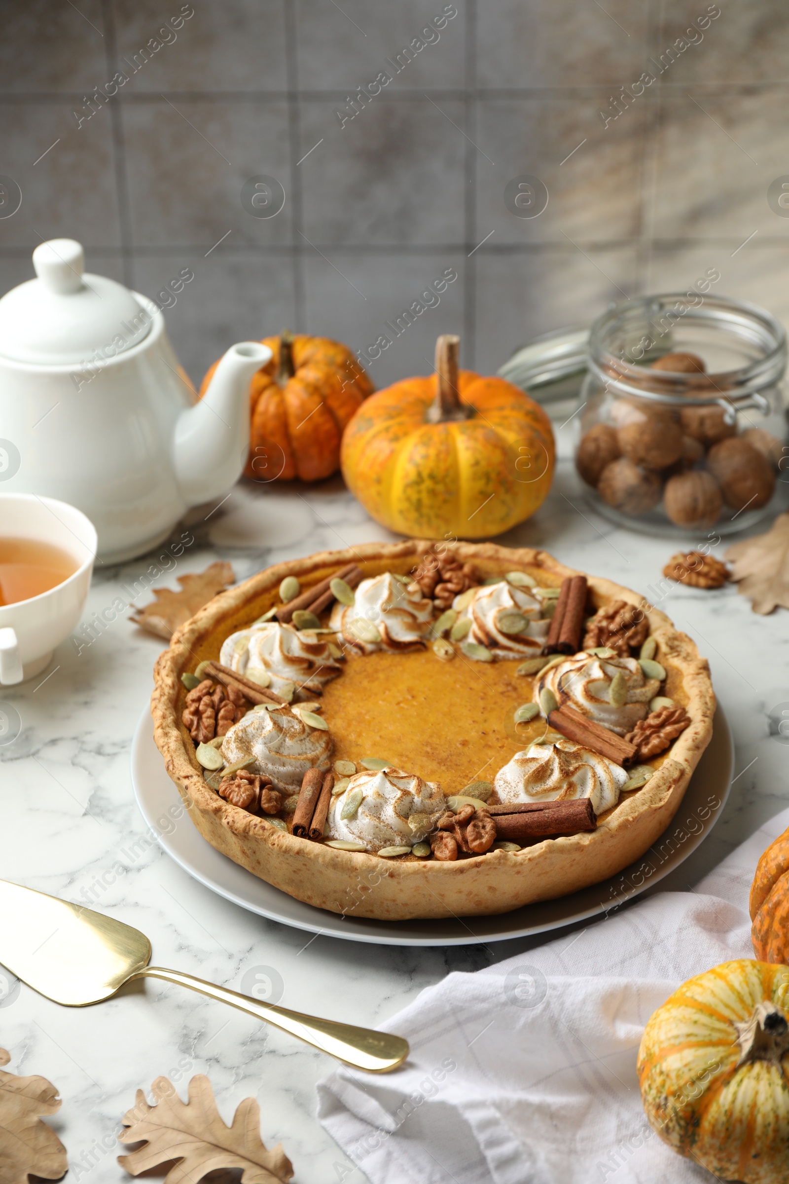 Photo of Homemade pumpkin pie with whipped cream, seeds and cinnamon on white marble table