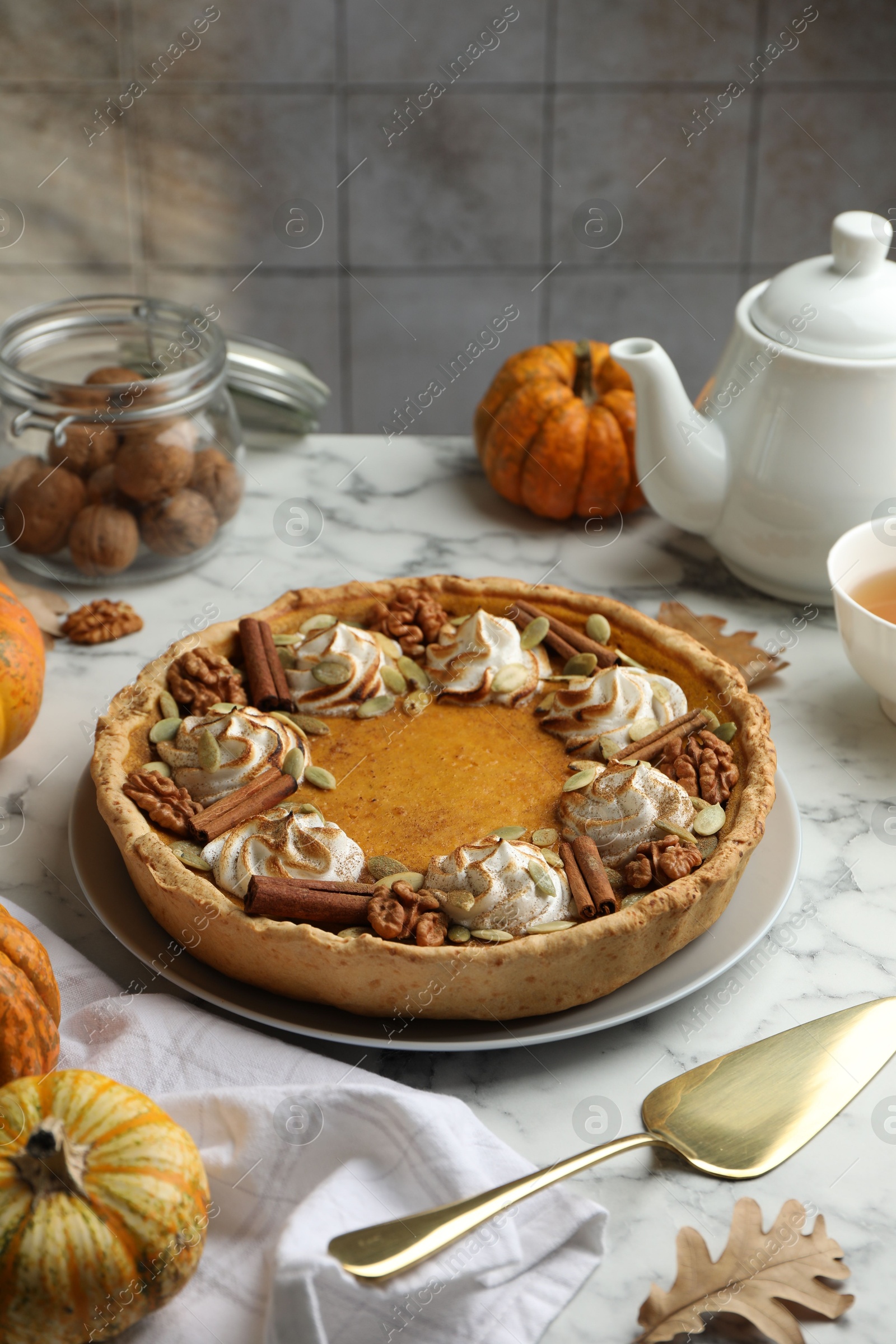 Photo of Homemade pumpkin pie with whipped cream, seeds and cinnamon on white marble table