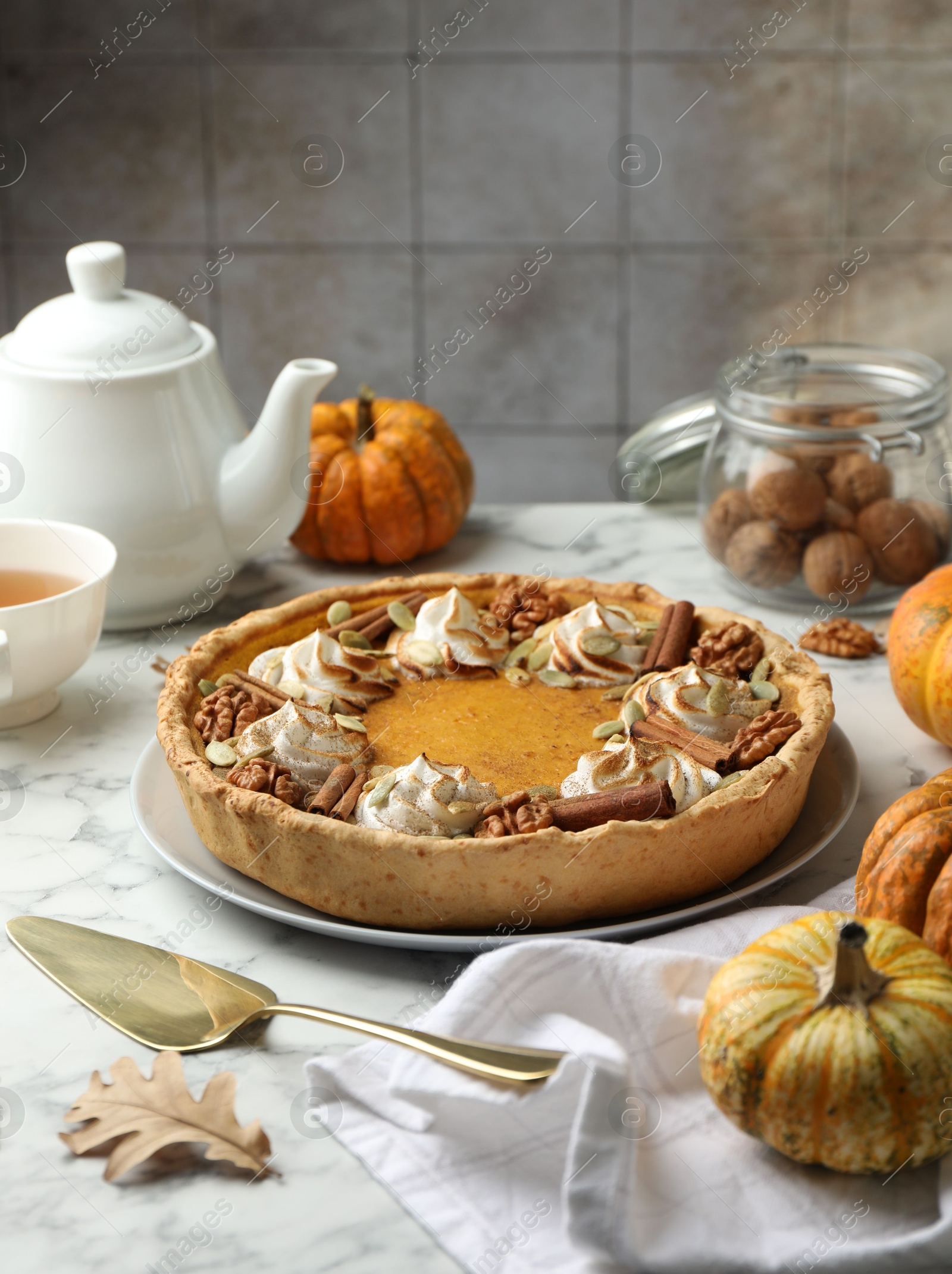 Photo of Homemade pumpkin pie with whipped cream, seeds and cinnamon on white marble table