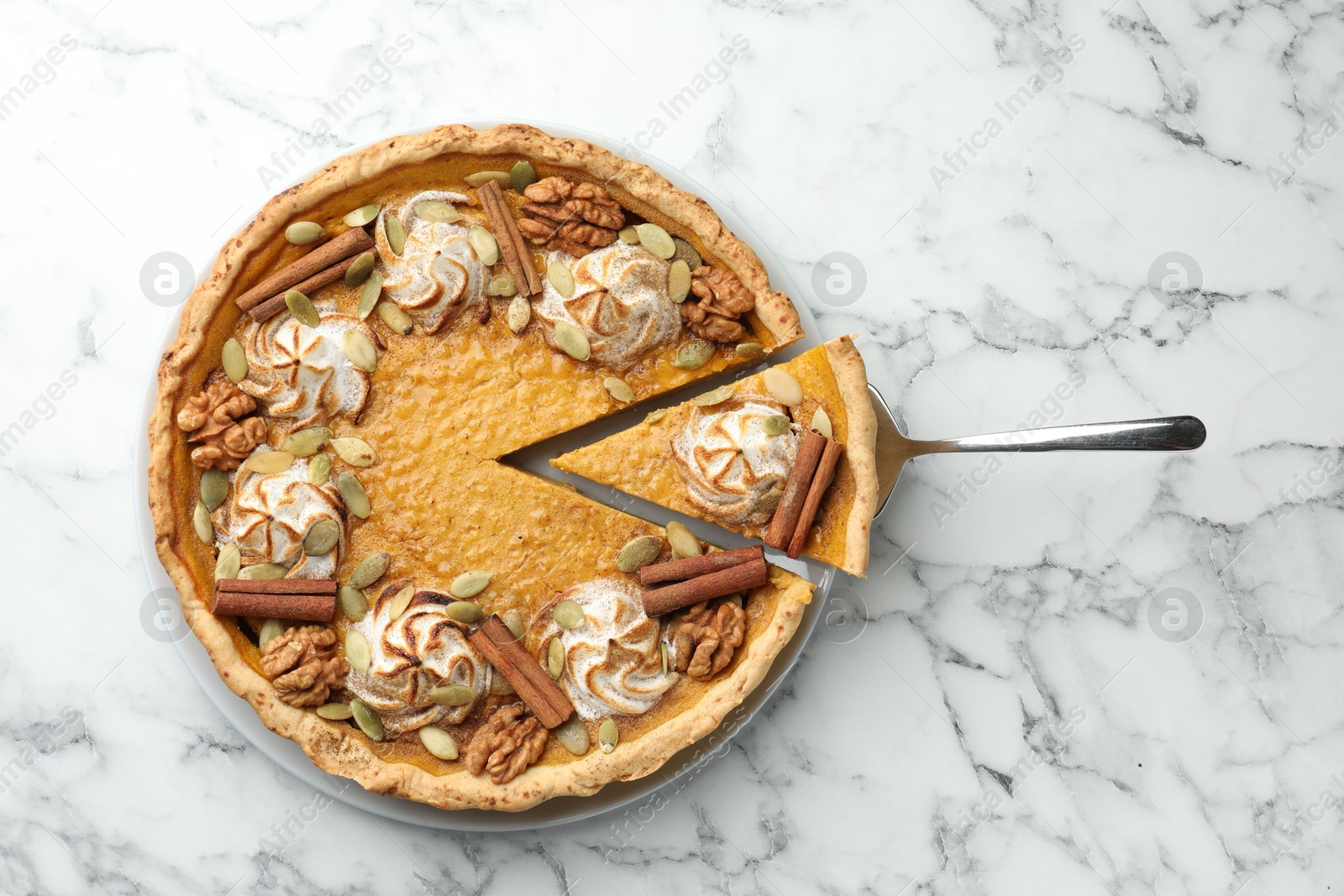 Photo of Tasty homemade pumpkin pie with server on white marble table, top view