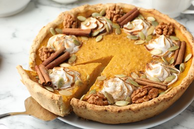 Tasty homemade pumpkin pie with server on white marble table, closeup