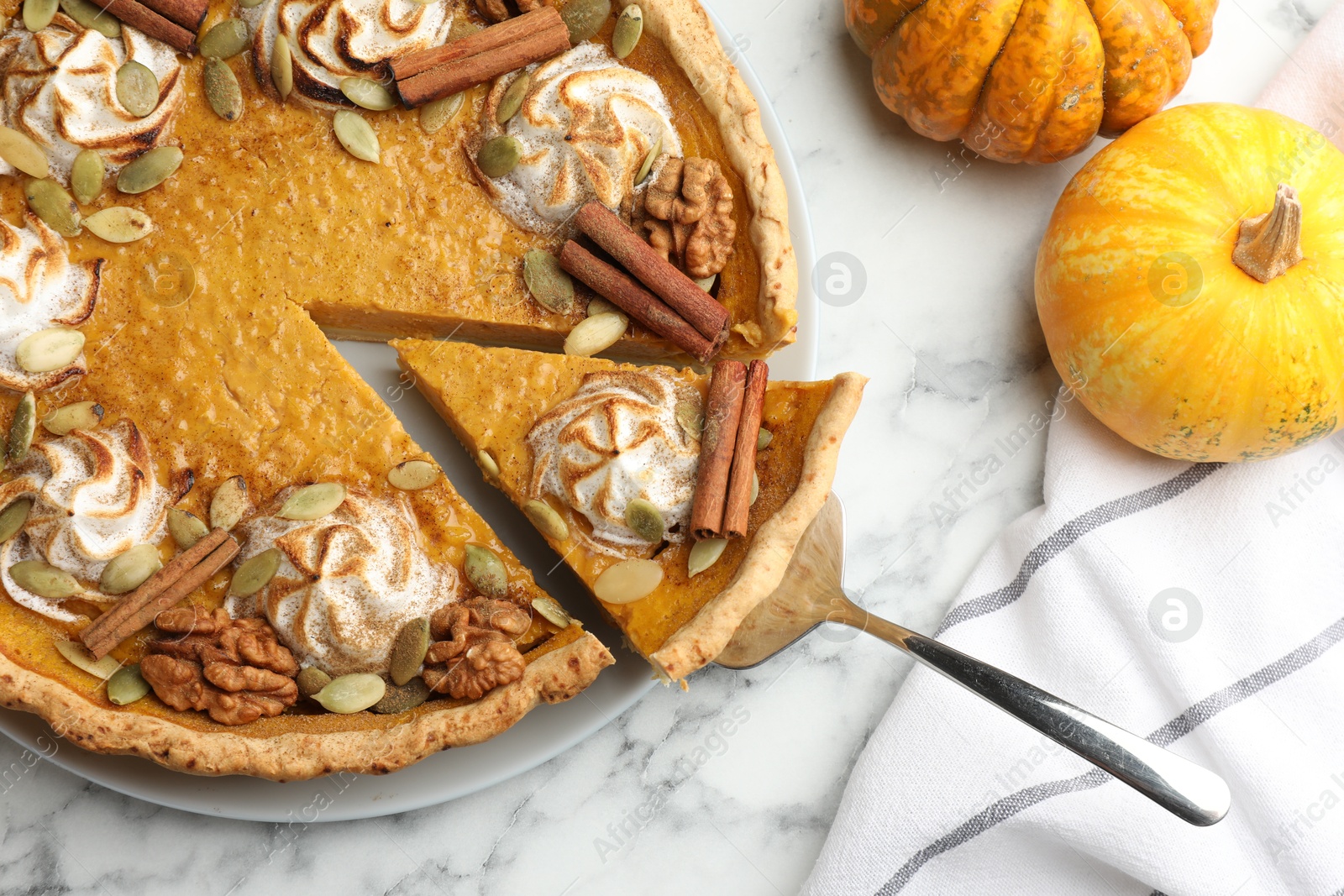 Photo of Tasty homemade pumpkin pie with ingredients and server on white marble table, flat lay