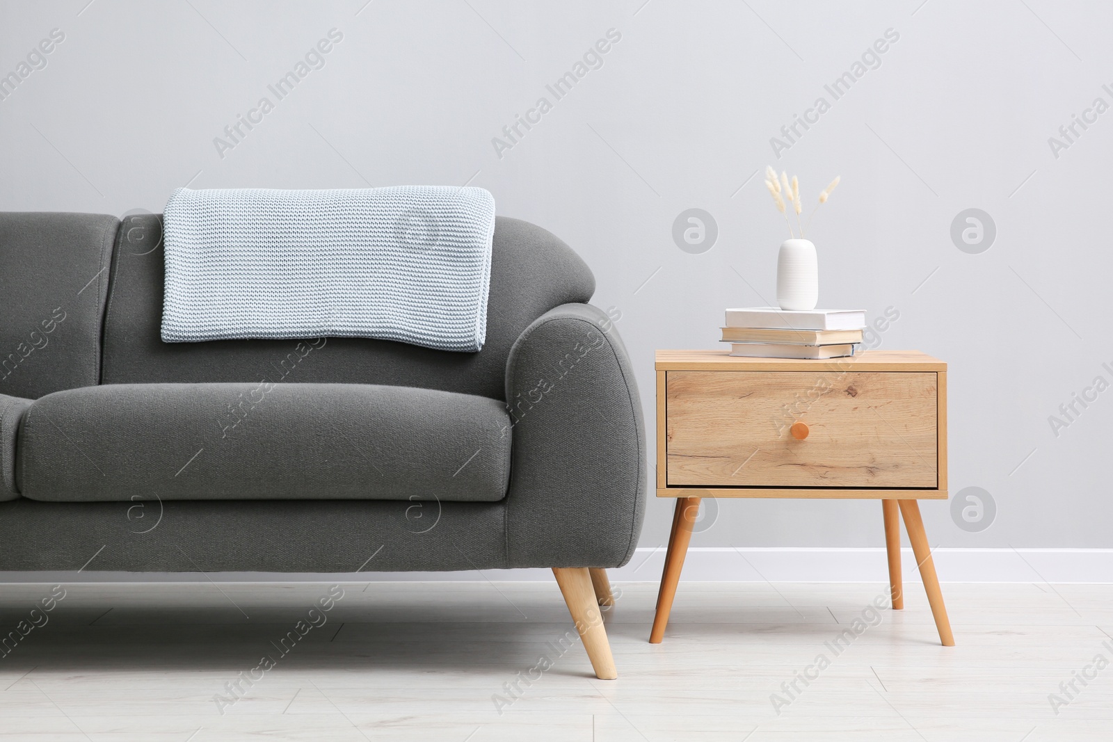 Photo of Comfortable sofa and table near grey wall in room