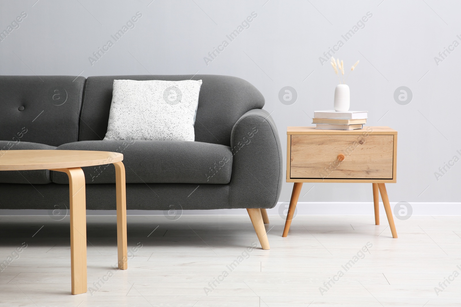 Photo of Comfortable sofa and tables near grey wall in room