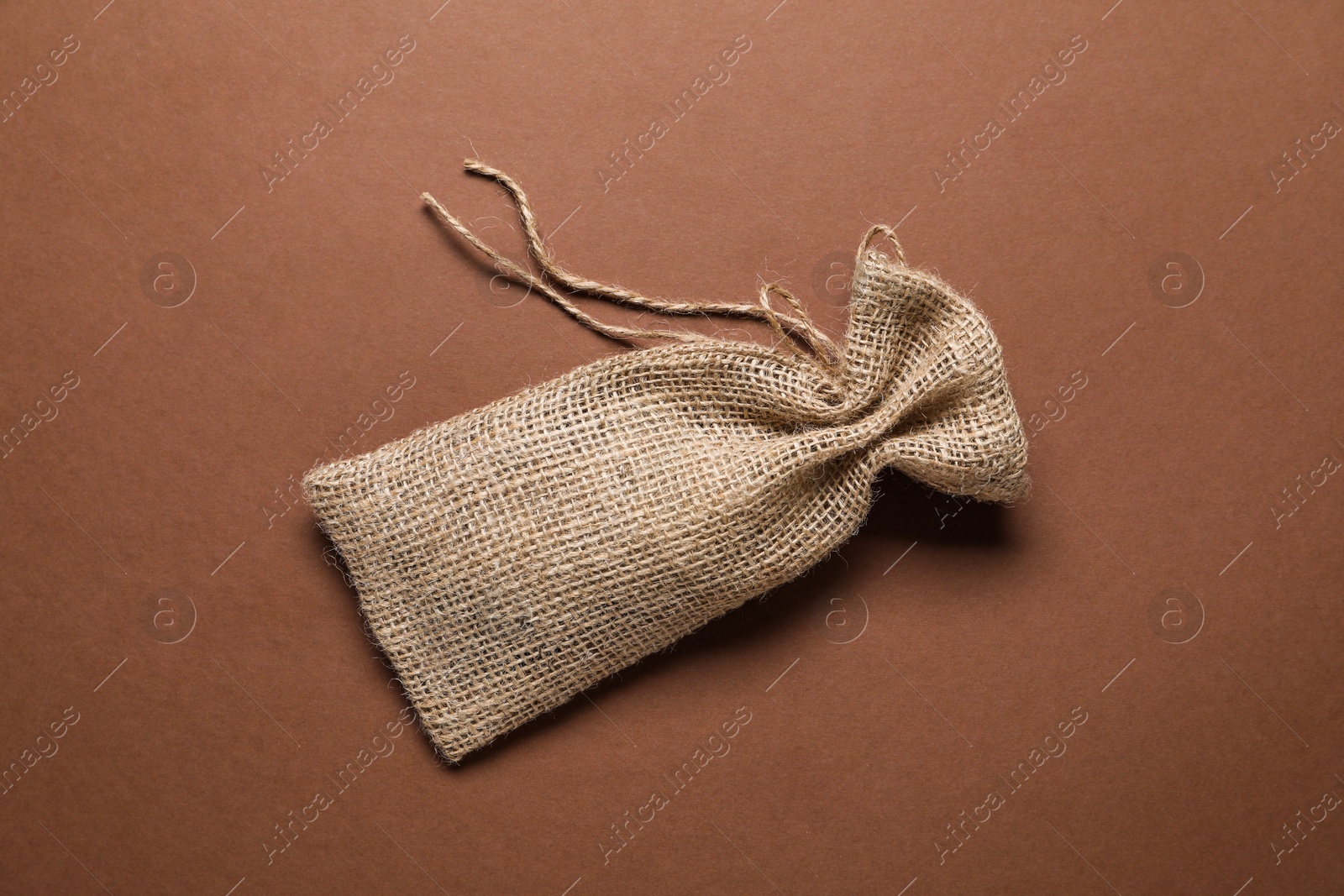 Photo of One burlap sack on brown background, top view