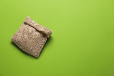 Photo of One burlap sack on light green background, top view. Space for text