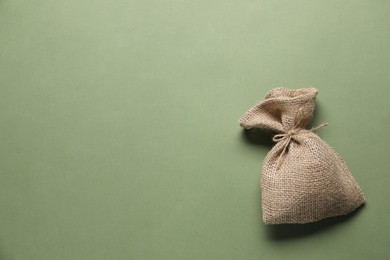 Photo of One burlap sack on olive background, top view. Space for text