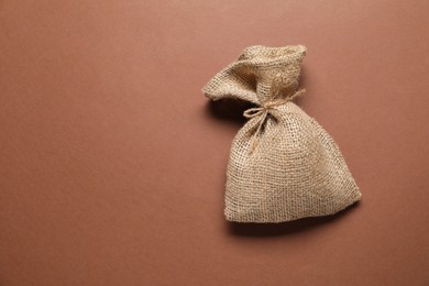 Photo of One burlap sack on brown background, top view. Space for text