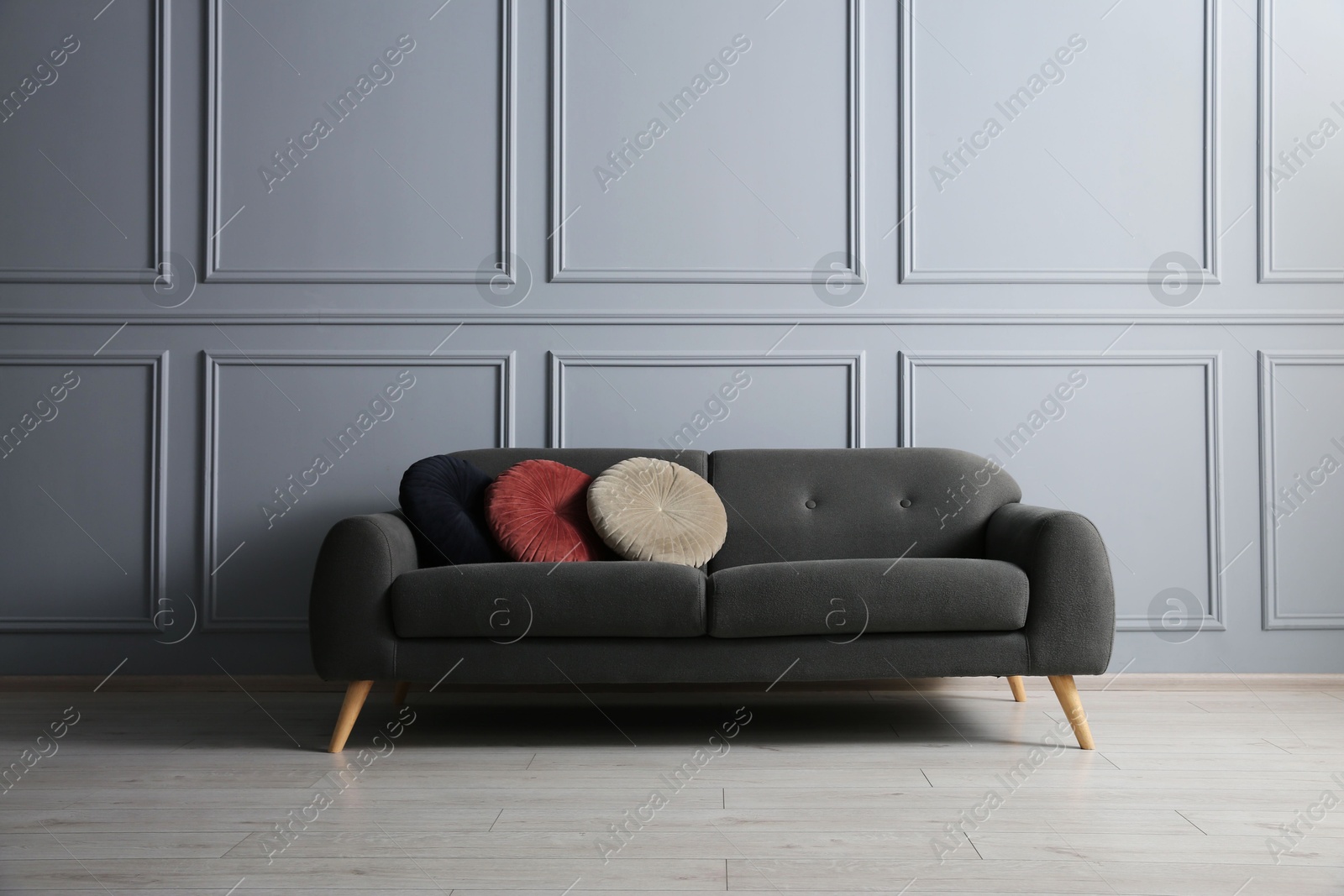 Photo of Stylish sofa with cushions near grey wall