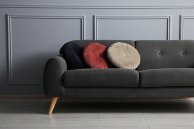 Stylish sofa with cushions near grey wall