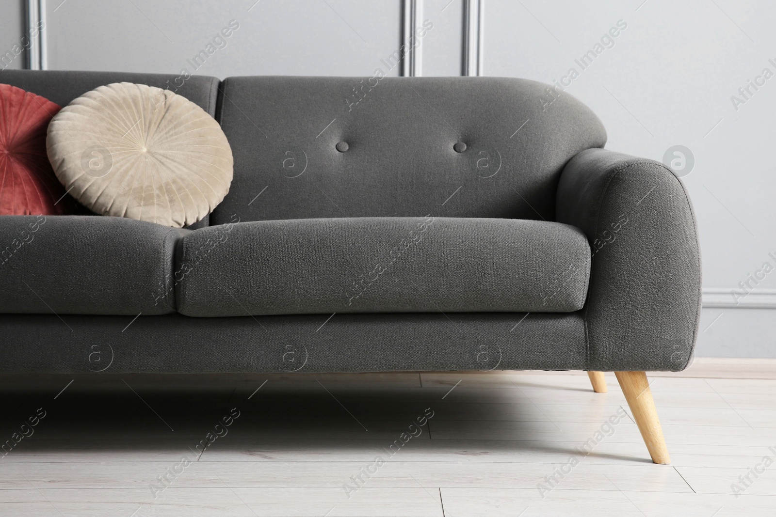 Photo of Stylish sofa with cushions near grey wall