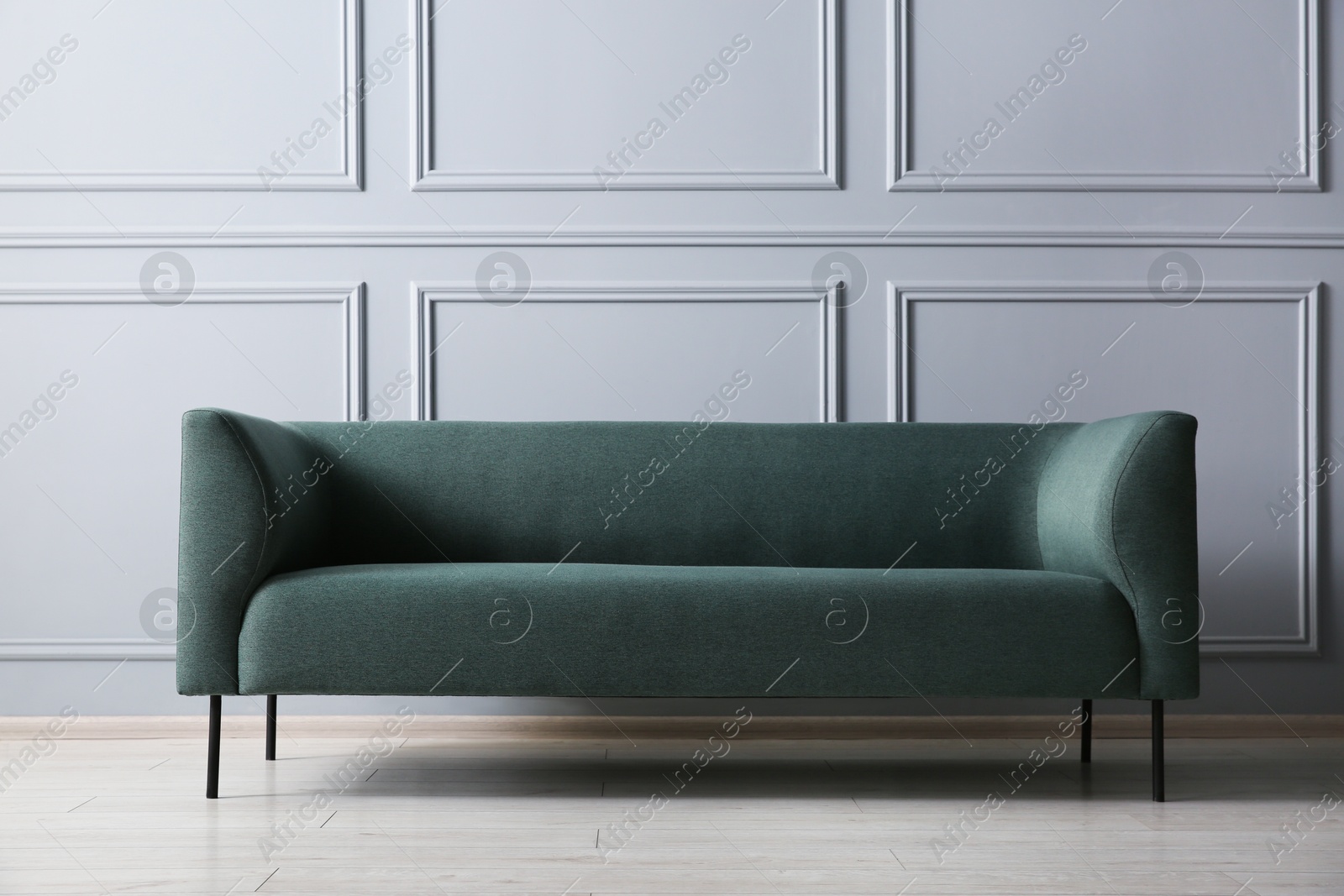 Photo of One stylish sofa near grey wall indoors