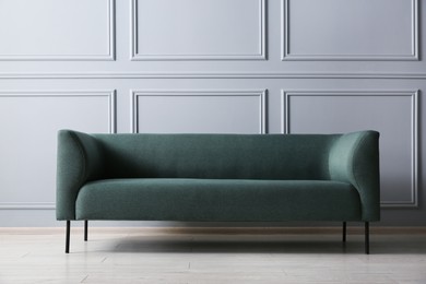 One stylish sofa near grey wall indoors