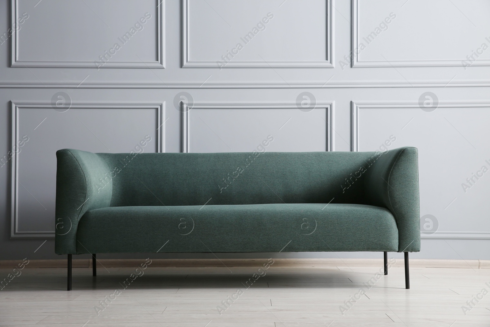 Photo of One stylish sofa near grey wall indoors