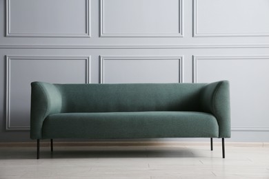 One stylish sofa near grey wall indoors