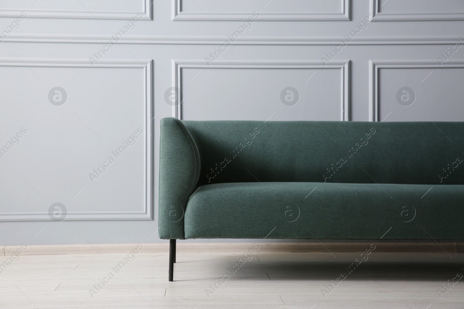 Photo of One stylish sofa near grey wall indoors