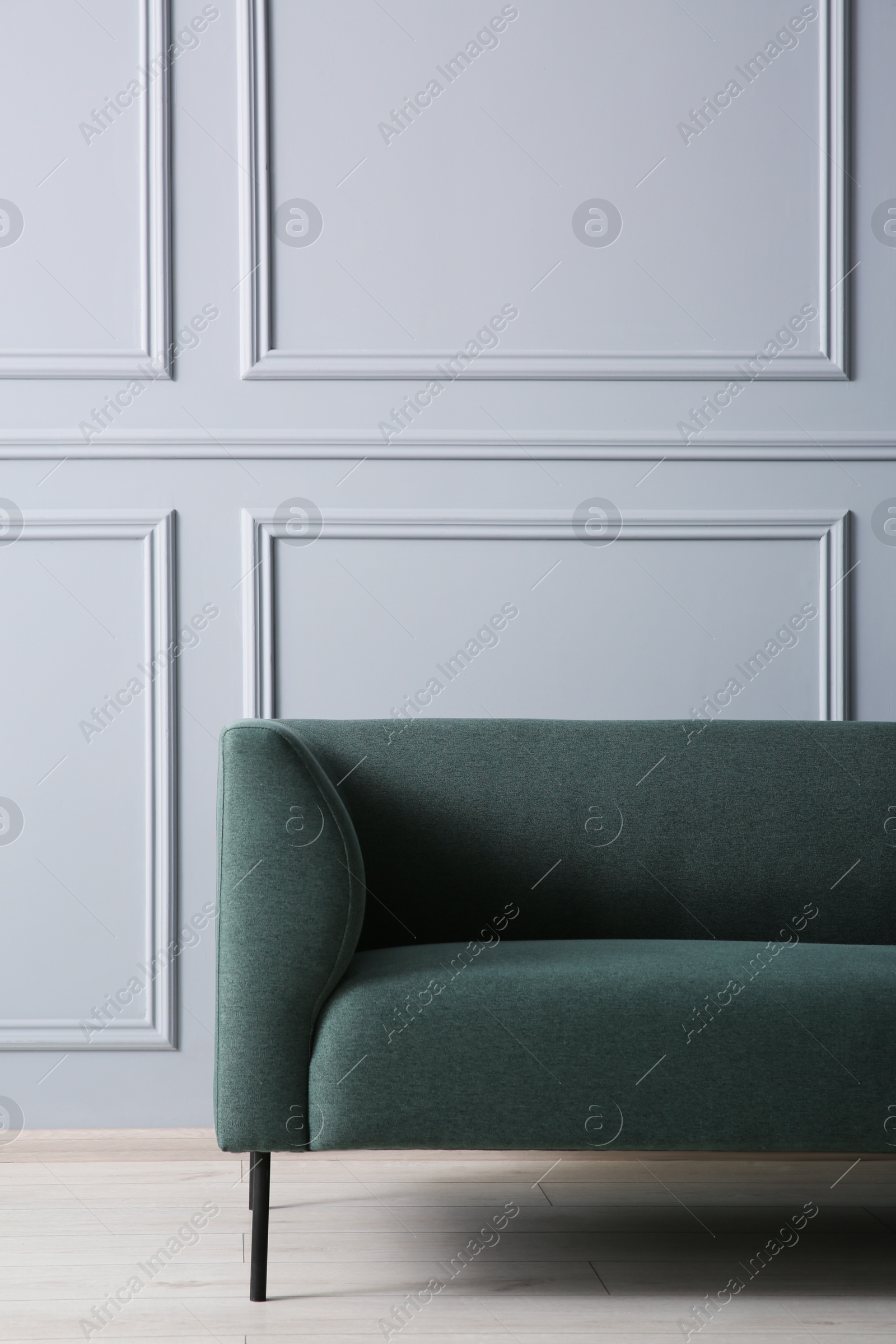 Photo of One stylish sofa near grey wall indoors