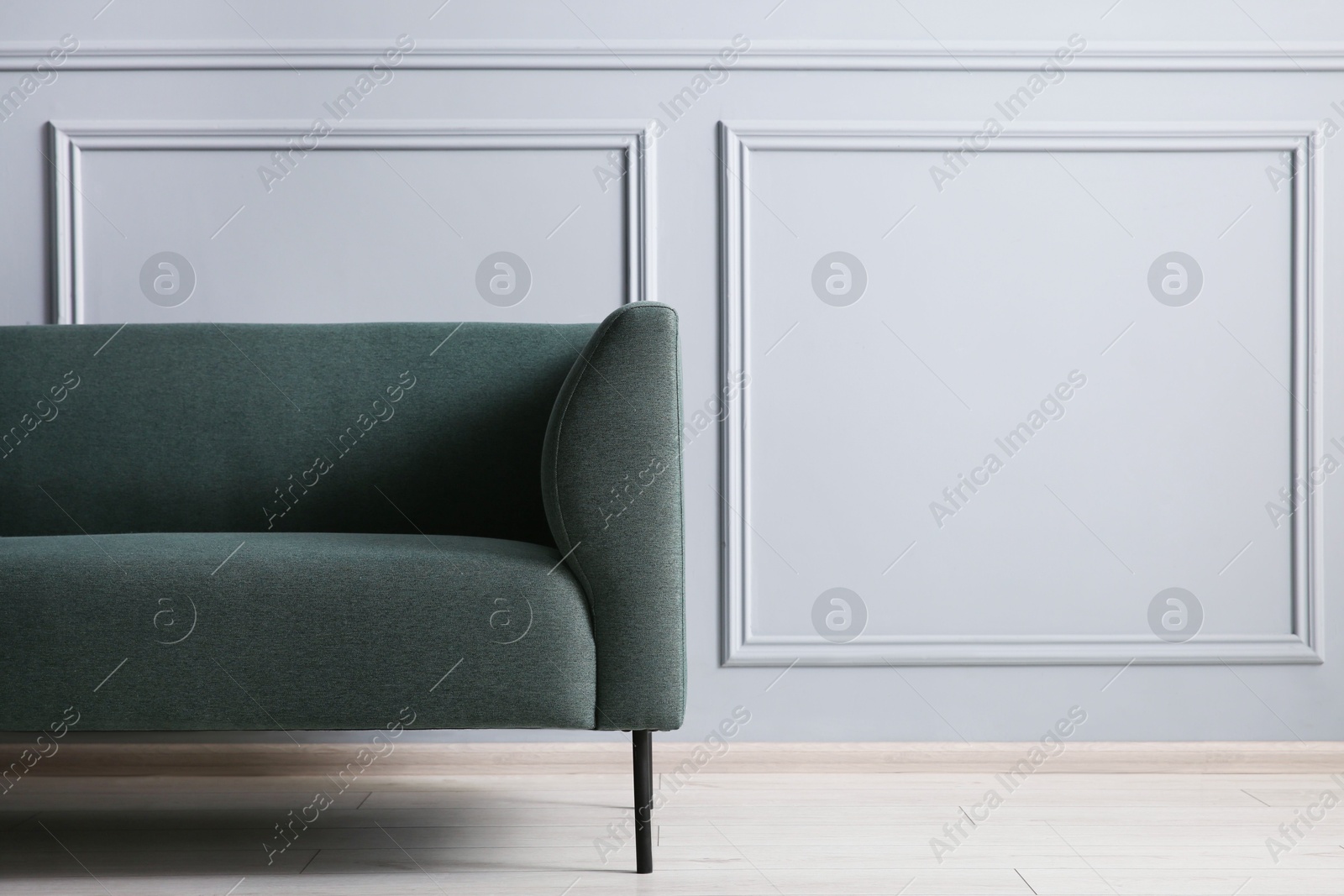 Photo of One stylish sofa near grey wall, space for text