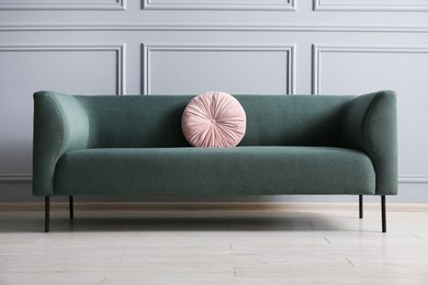 Photo of Stylish sofa with cushion near grey wall