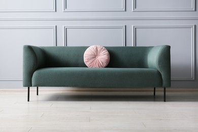 Stylish sofa with cushion near grey wall