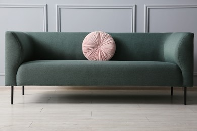 Stylish sofa with cushion near grey wall