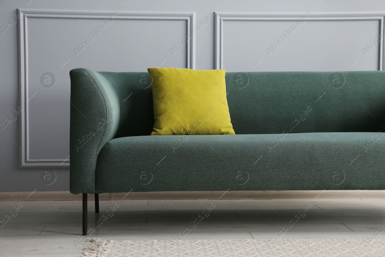 Photo of Stylish sofa with cushion near grey wall