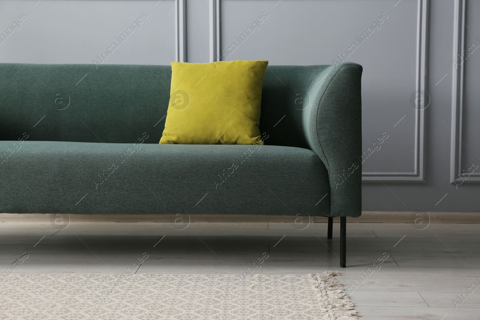 Photo of Stylish sofa with cushion near grey wall