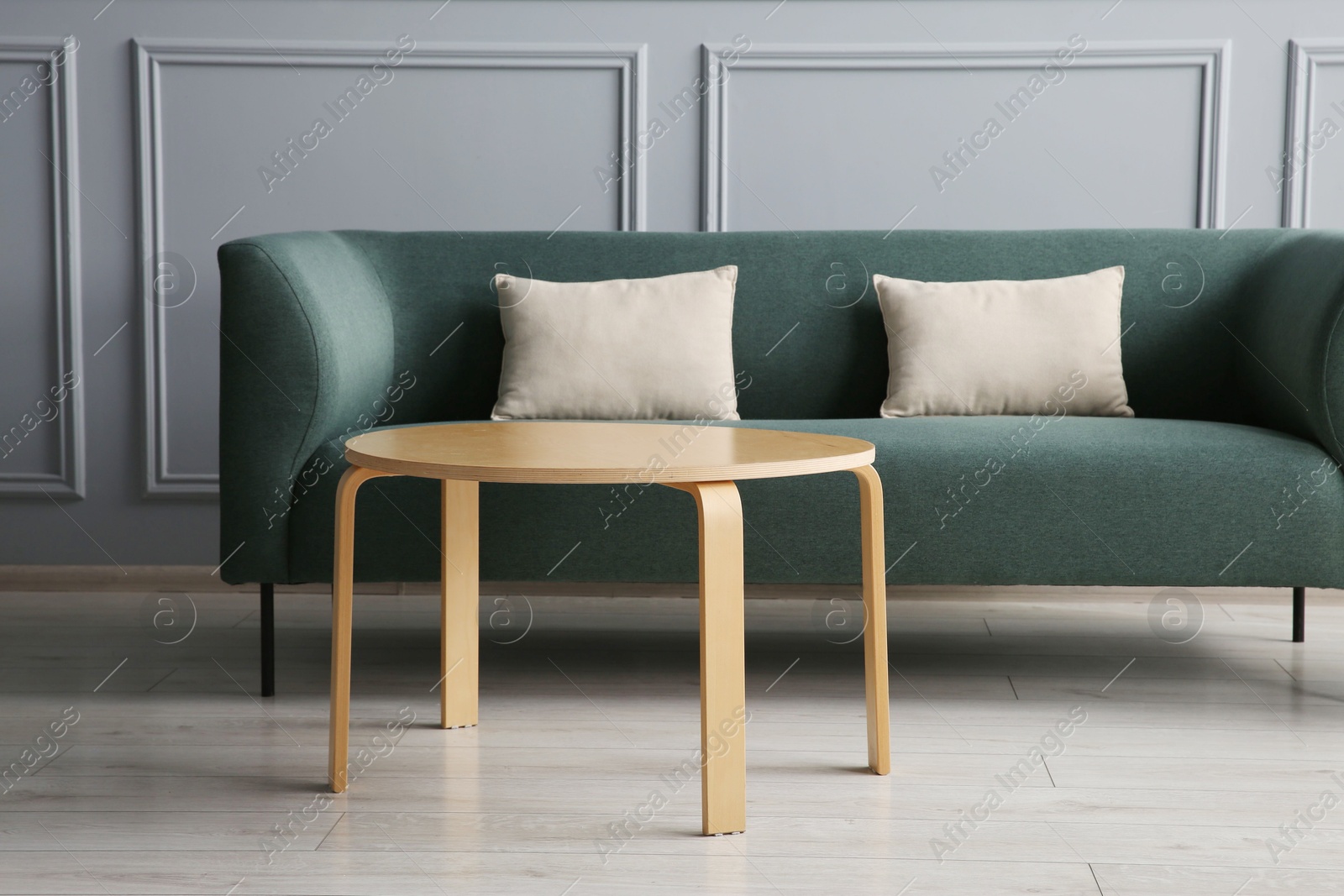 Photo of Stylish sofa with cushions and coffee table in room