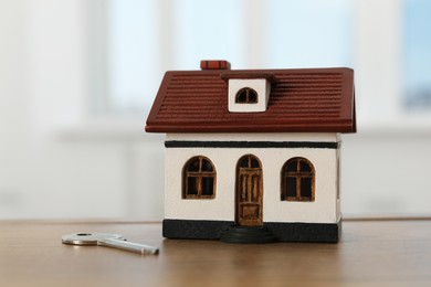 Photo of House model and key on wooden table indoors