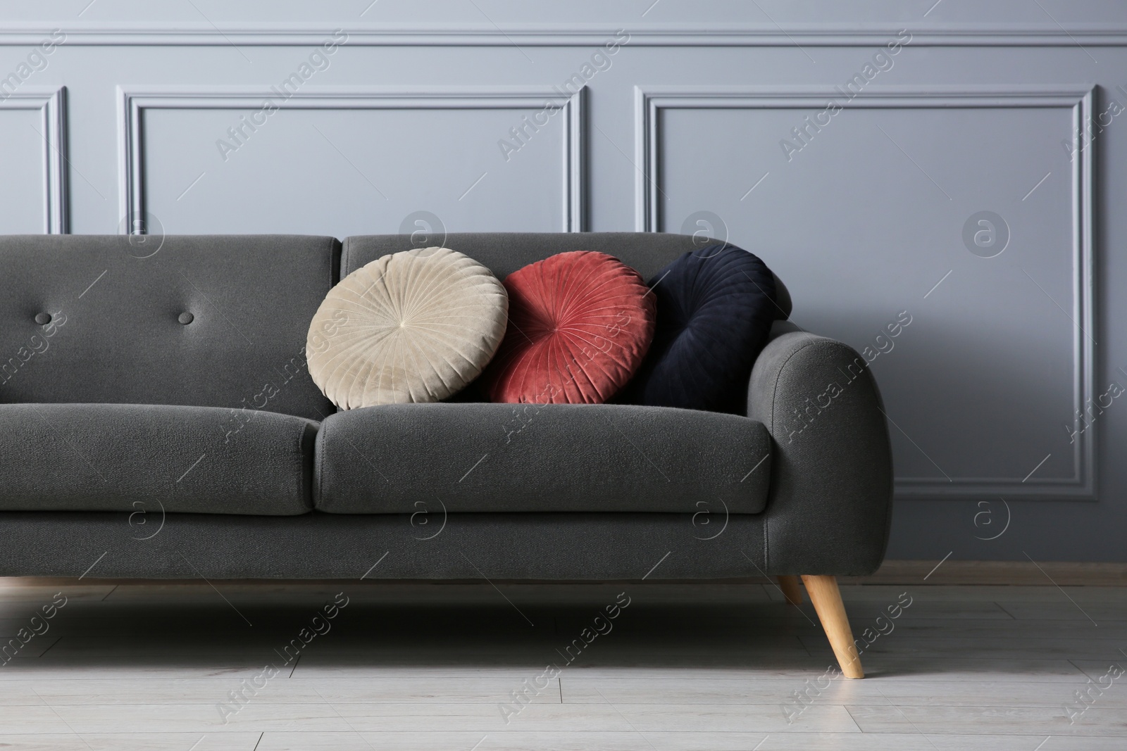 Photo of Stylish sofa with cushions near grey wall