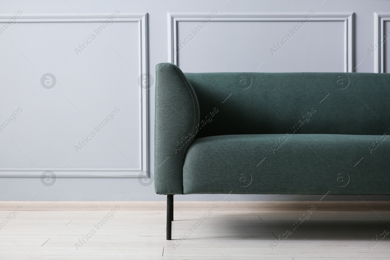 Photo of One stylish sofa near grey wall, space for text