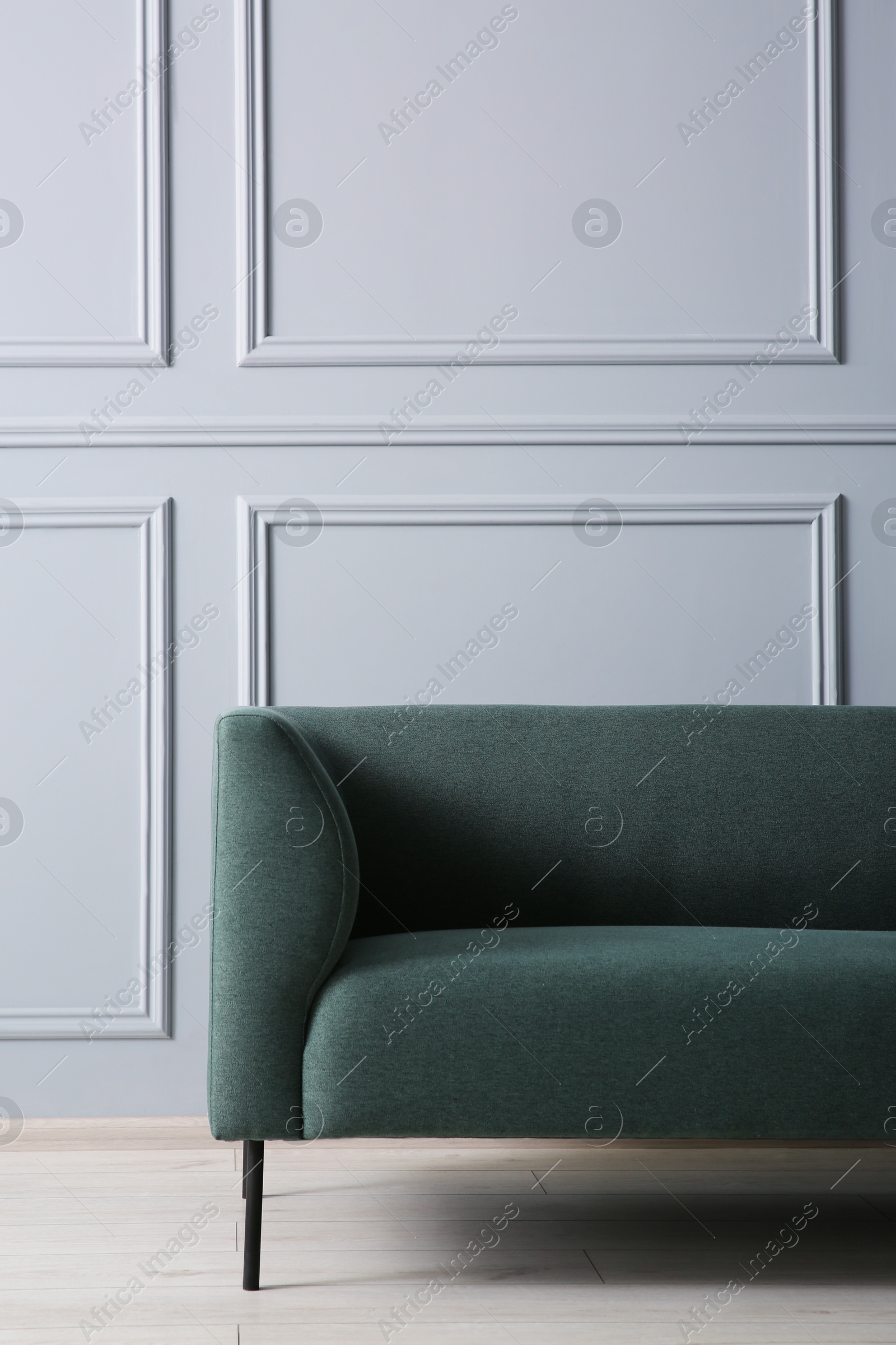 Photo of One stylish sofa near grey wall indoors