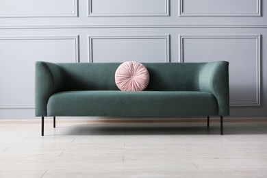 Photo of Stylish sofa with cushion near grey wall