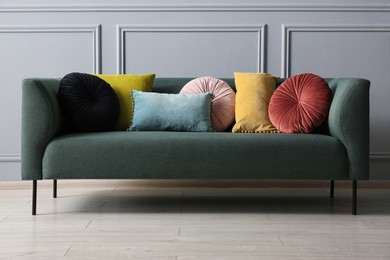 Photo of Stylish sofa with different cushions near grey wall