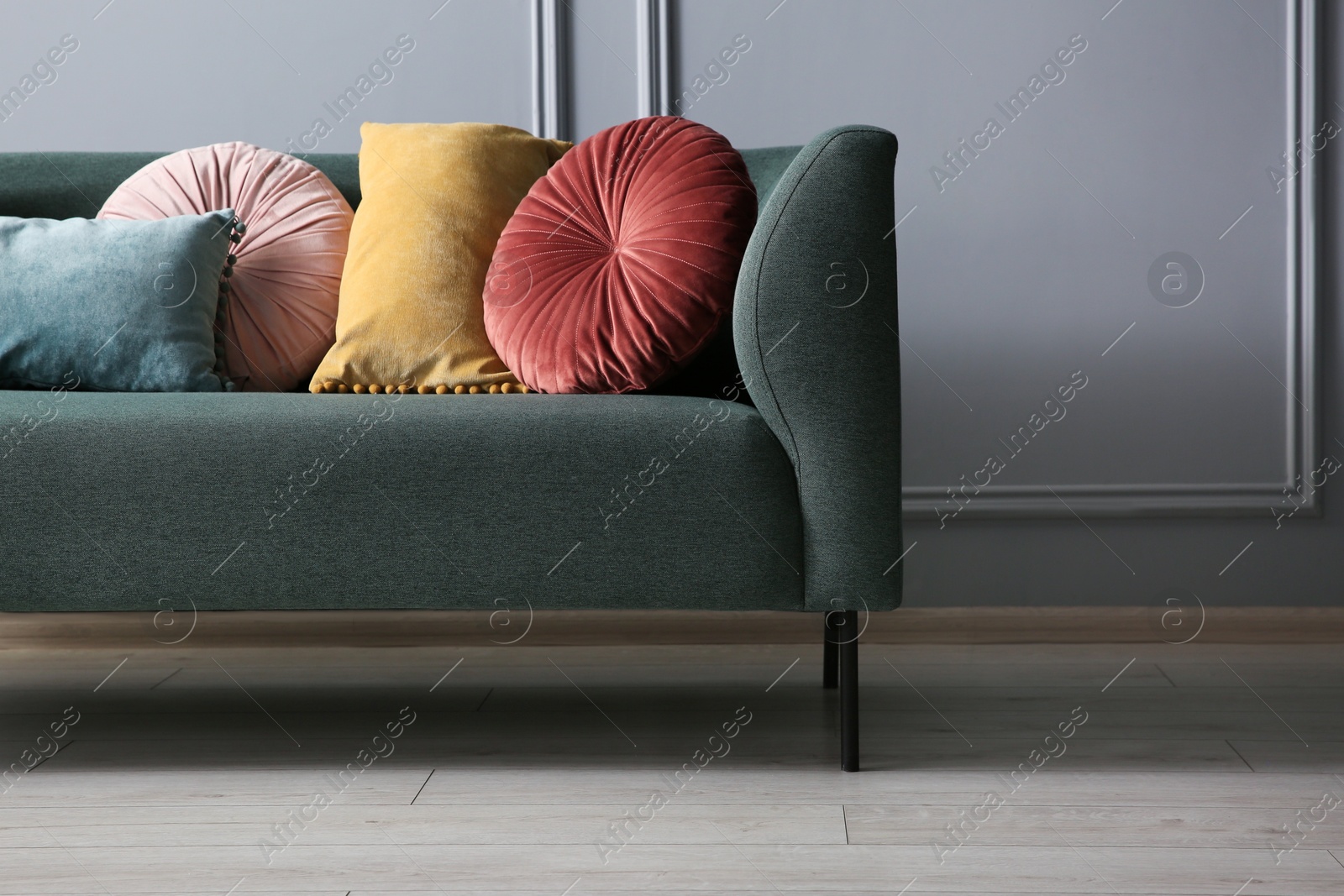 Photo of Stylish sofa with different cushions near grey wall