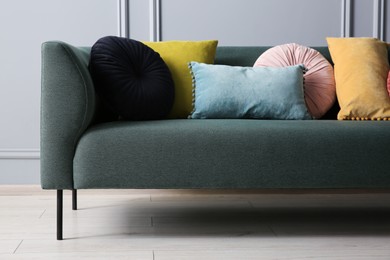 Photo of Stylish sofa with different cushions near grey wall