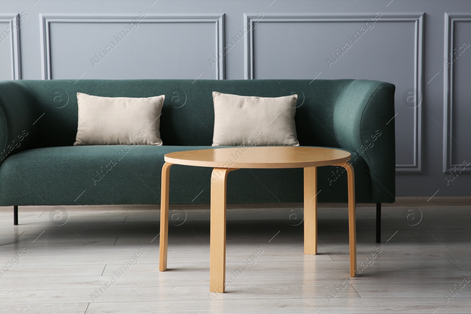 Photo of Stylish sofa with cushions and coffee table in room