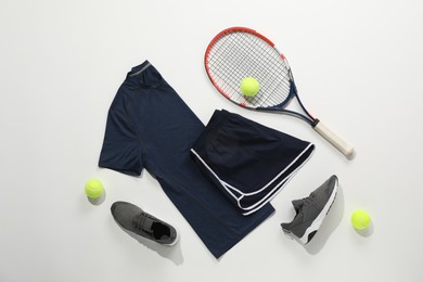 Photo of Tennis racket, balls, sneakers and sportswear on light background, flat lay