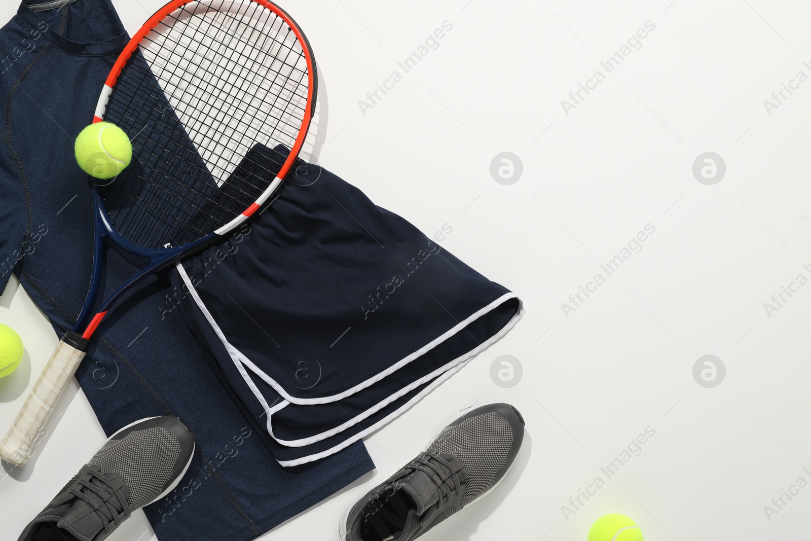 Photo of Tennis racket, balls, sneakers and sportswear on light background, flat lay. Space for text