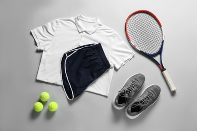 Photo of Tennis racket, balls, sneakers and sportswear on grey background, flat lay