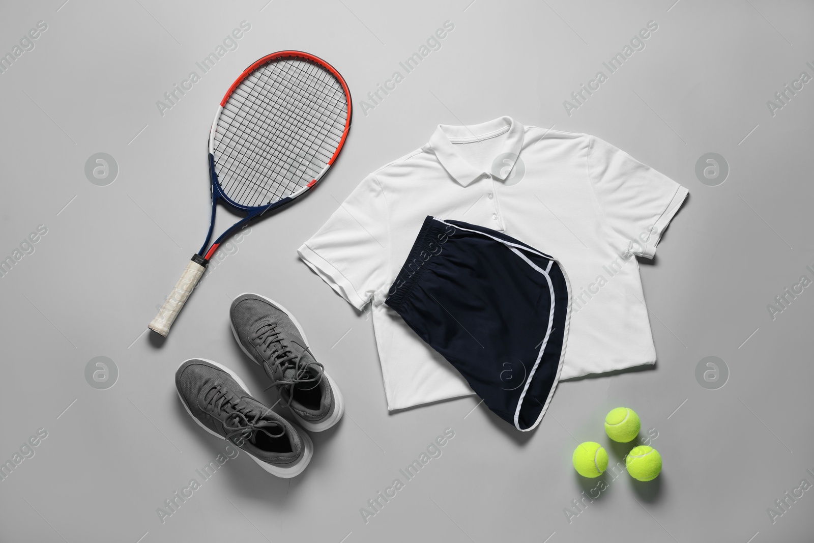 Photo of Tennis racket, balls, sneakers and sportswear on grey background, flat lay